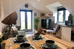 Open plan living/dining area with balcony doors leading out to small balcony with chairs
